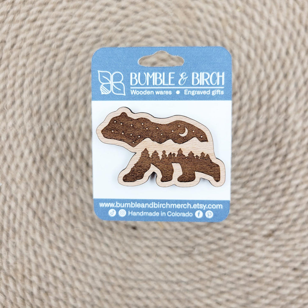 Bear shaped wood pin, with engraved mountains and night sky, in packaging