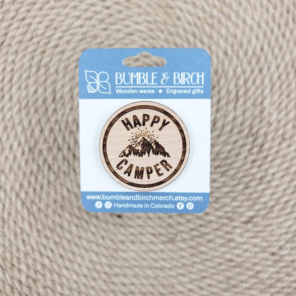 Happy camper round pin with engraved mountains and packaging