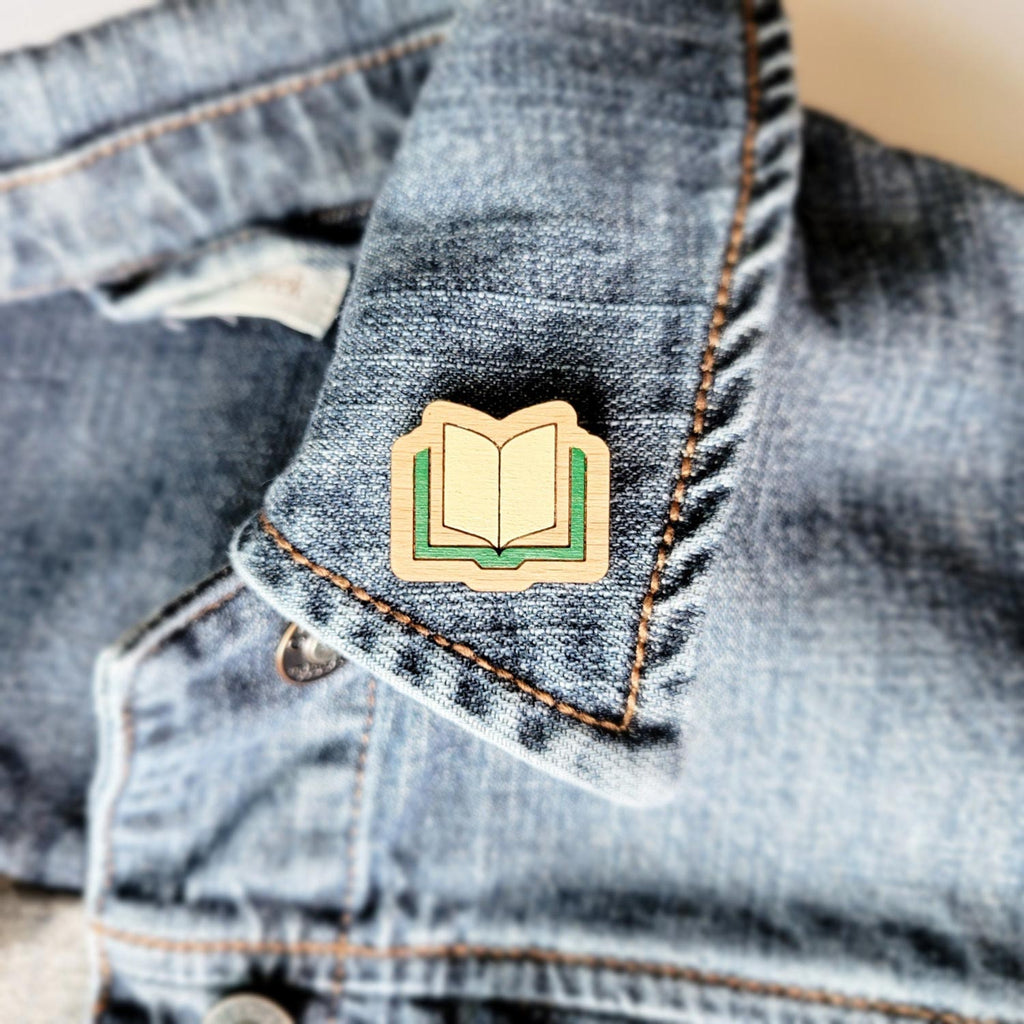 Green book shaped, engraved wooden pin on a jacket