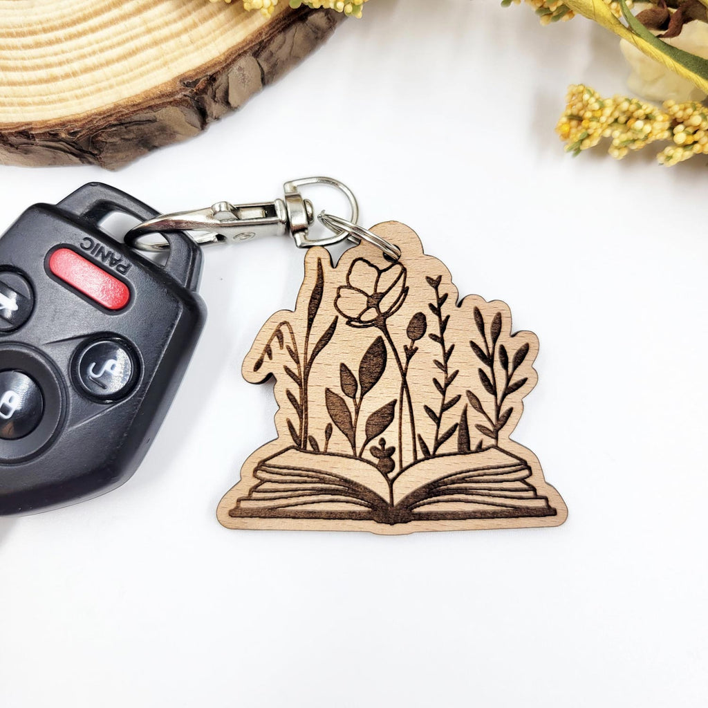 Flowers emerging from an open book engraved wooden keychain