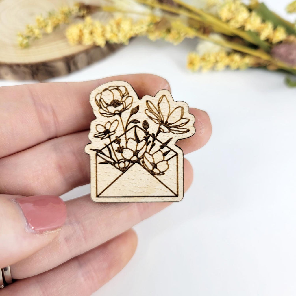 Flowers emerging from a letter- engraved wooden pin